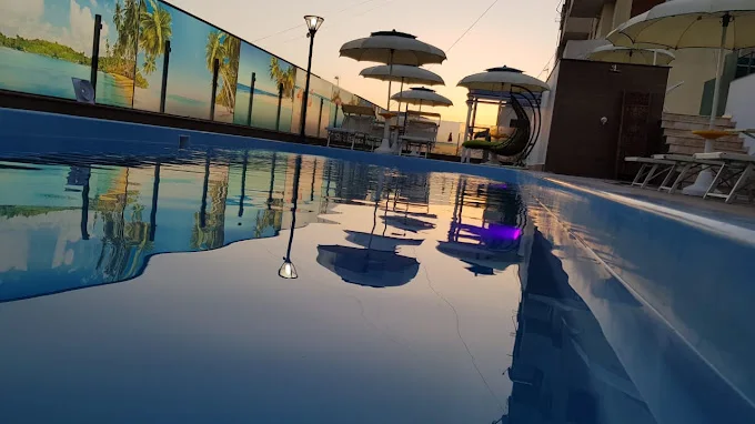 Pishina në tarracën e hotelit Antalya në perëndim, me shezlongë dhe çadra